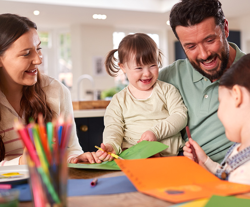 Photograph of a family with a disabled child enjoying art around the kitchen table